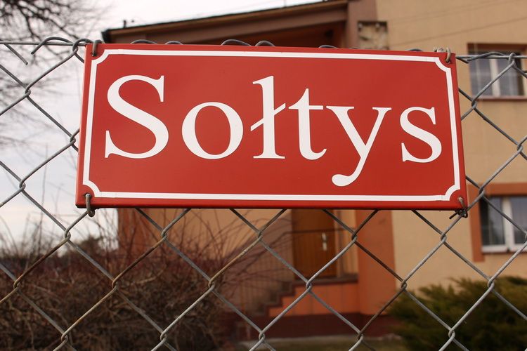 Czerwona tabliczka powieszona na bramie sołtys